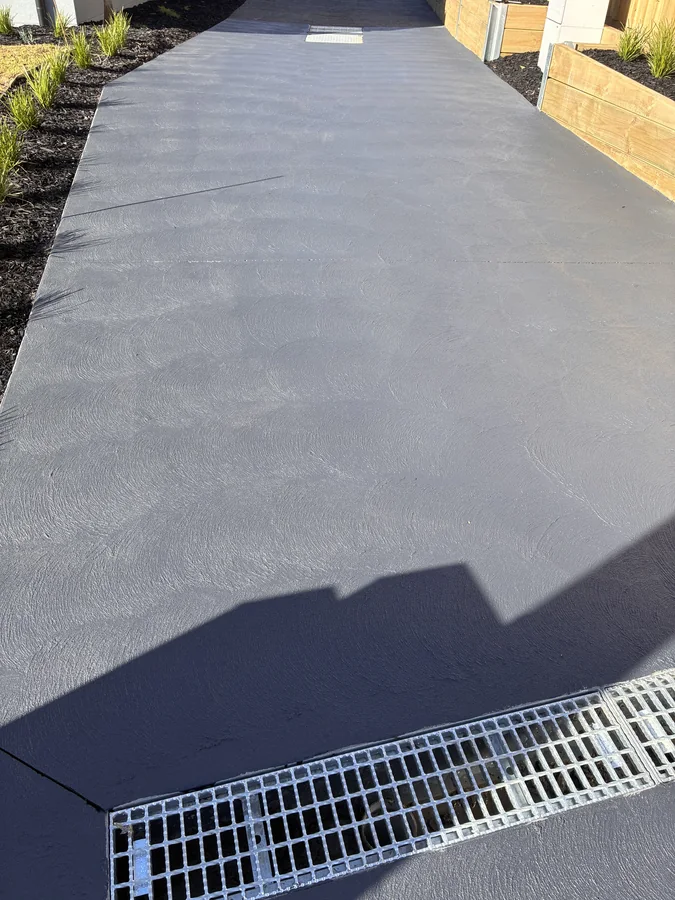 Concrete driveway receiving a fresh dark sealing coat