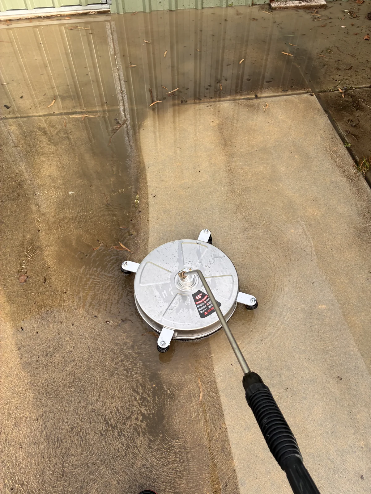Concrete surface being pressure washed with a rotary surface cleaner